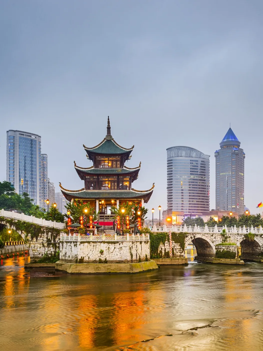 The Jiaxiu pavilion on the Nanming river in Guiyang, with the towers behind at dusk